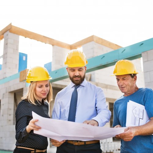 Architect, civil engineer and worker looking at plans and blueprints, discussing issues at the construction site.